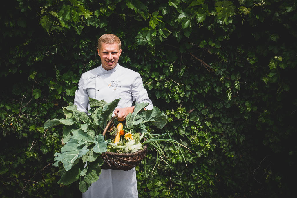 Der Koch Daniel Reuner hält einen großen Korb mit Gemüse aus dem Garten